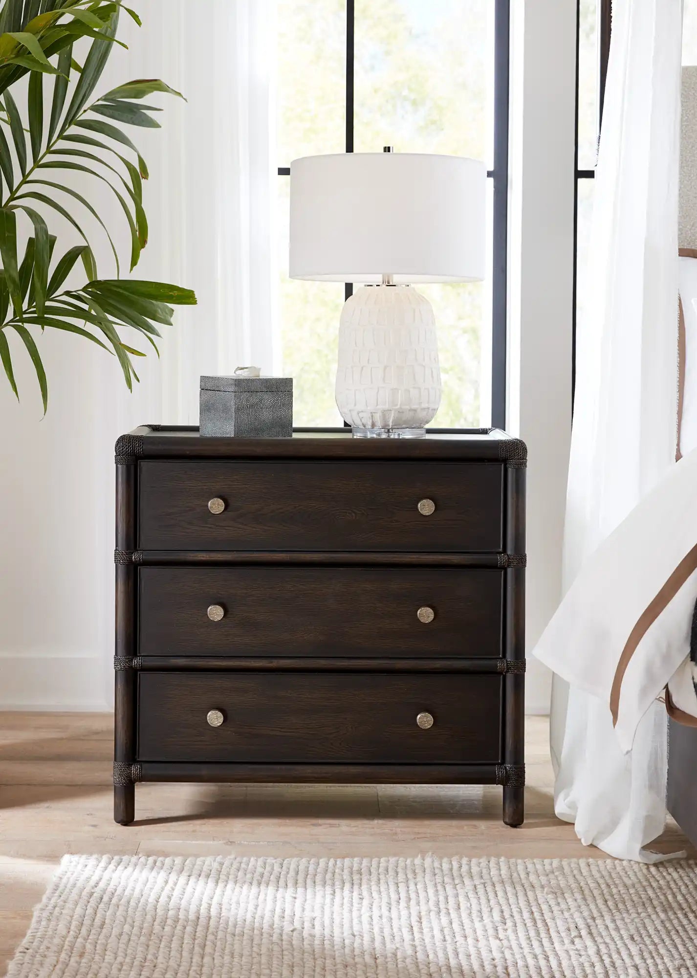 Dark wood nightstand with three drawers and silver knobs