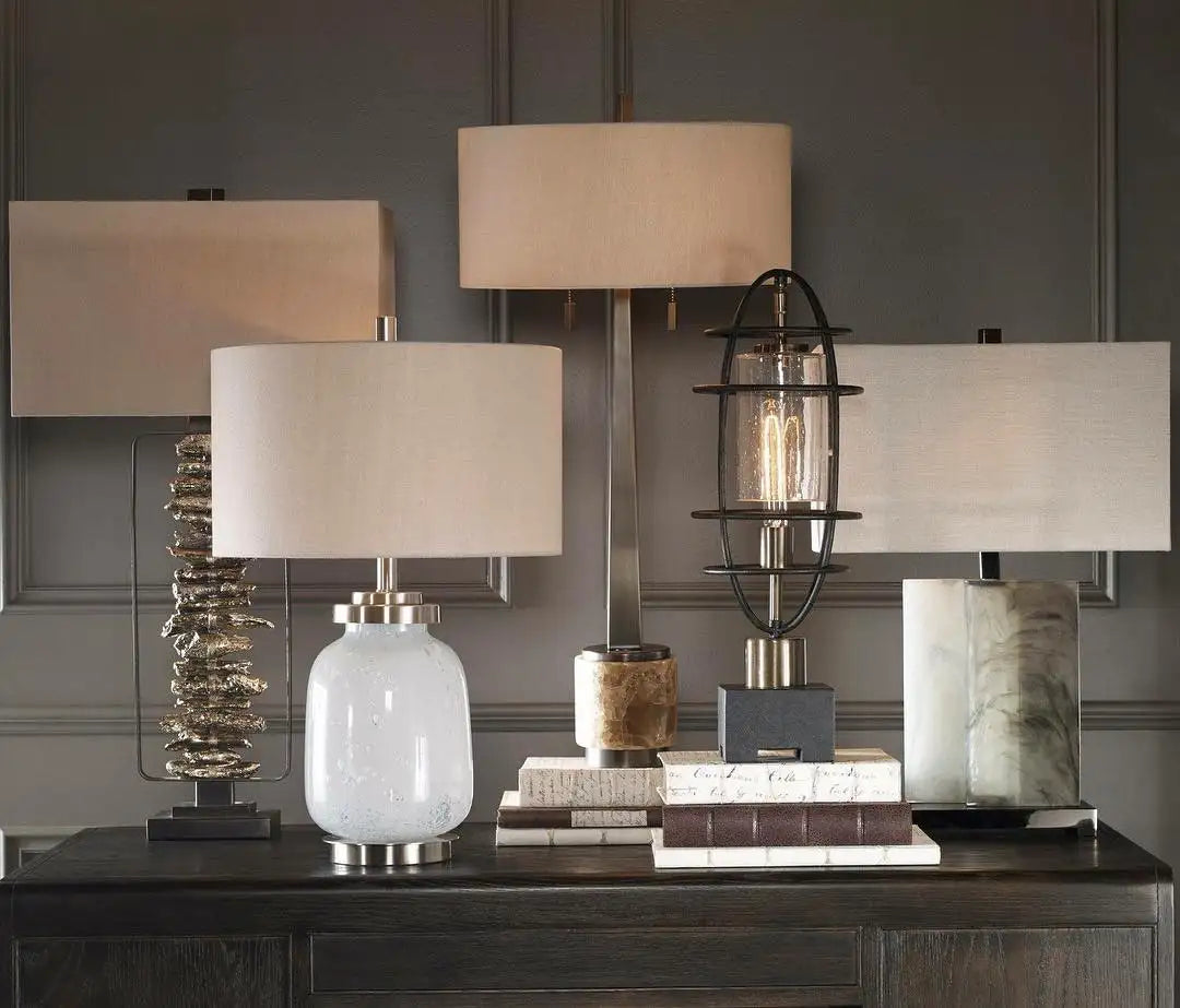 A sleek, frosted white glass table lamp with a brushed metal base and a cylindrical off-white fabric shade.