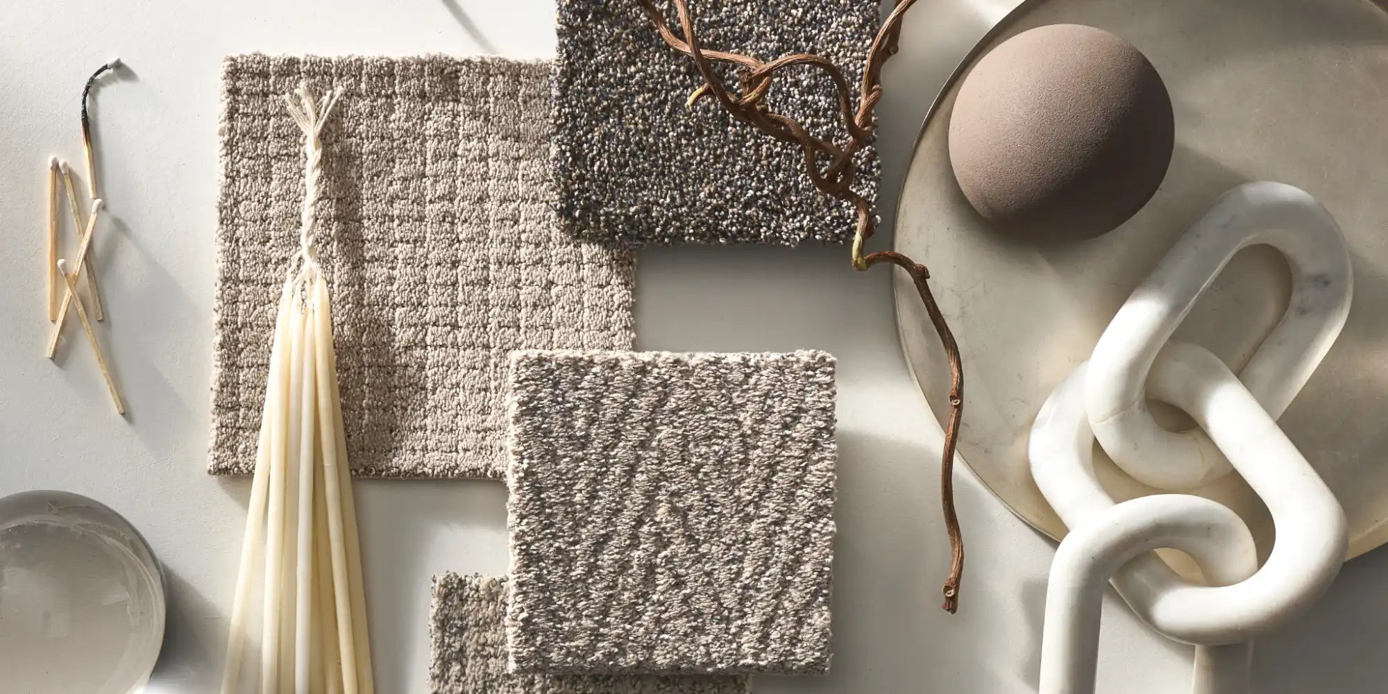 Textured carpet samples in neutral tones, accompanied by decorative objects.